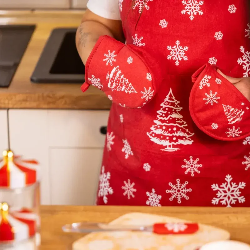 Czerwone rękawice kuchenne z motywami świątecznymi, śnieżynkami i choinkami, idealne na Boże Narodzenie, w kuchni, przy pieczeniu i dekoracji świątecznej atmosfery.
