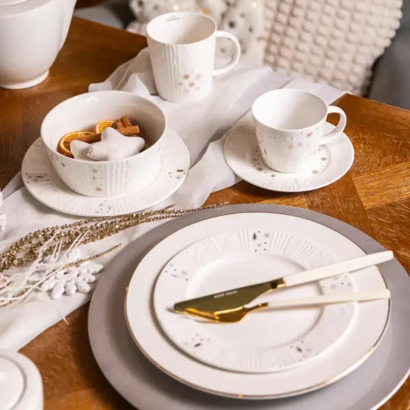 Delikatne zestawy świąteczne z porcelany Domowy Zakątek, talerze, filiżanki i miseczki w zimowym stylu, idealne do świątecznego stołu, elegancko ozdobione złotem i motywami śnieżynek.