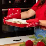 Przytulne rękawice kuchenne z motywem śnieżynek, idealne na zimowe święta, chronią dłonie podczas pieczenia i gotowania. Rękawice w czerwonym kolorze dodają świątecznego uroku kuchni.