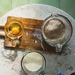Ekspres do pieczenia domowego ciasta, składniki do wypieku, mąka, jajko i mleko na stole, kuchnia domowa, zdrowe i naturalne składniki, domowe pieczenie, kulinarne inspiracje, wypieki, domowy zakątek, przepisy na ciasta i ciasteczka.