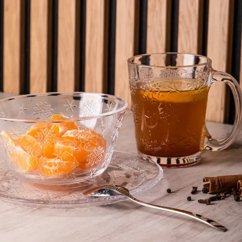 Podgrzewany napój zimowy z przyprawami, herbata w szklanym mug'u, mandarynki w miseczce, cynamon i goździki na świąteczny klimat, zimowe herbaty, domowe napoje, świąteczne smaki, sklep domowy zakątek.