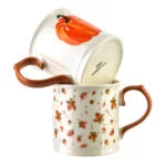 Podwójny kubek ceramiczny z jesiennym motywem liści i pomarańczowymi uchwytami, idealny na kawę lub herbatę w domu Domowy Zakątek.