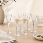 Szkło do szampana i wina na eleganckim stole, idealne do serwowania napojów alkoholowych, z delikatnym zdobieniem i wysoką jakością wykonania, na tle jasnej, minimalistycznej aranżacji.